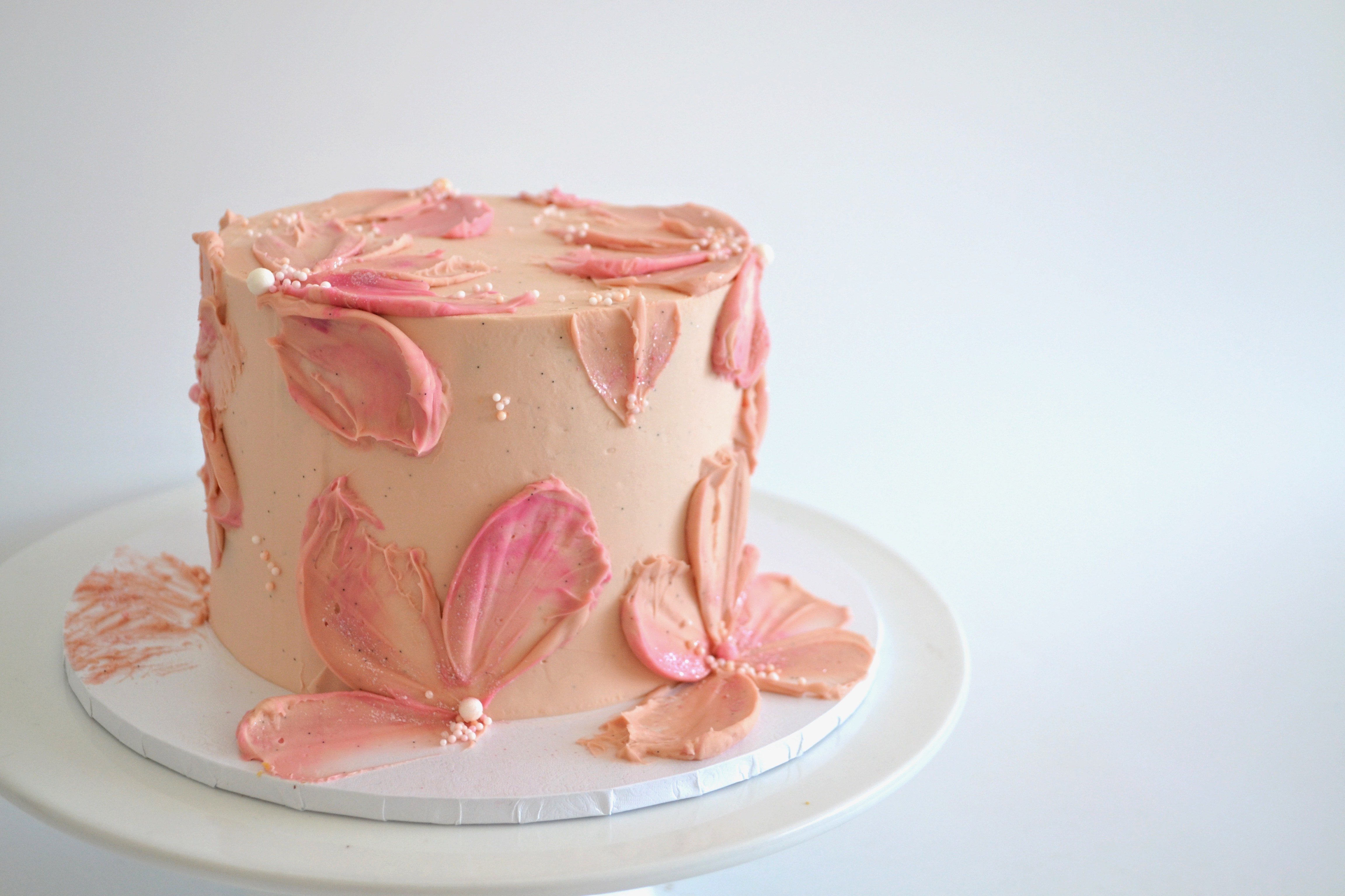 Pink floral cake on a white plate with a white background