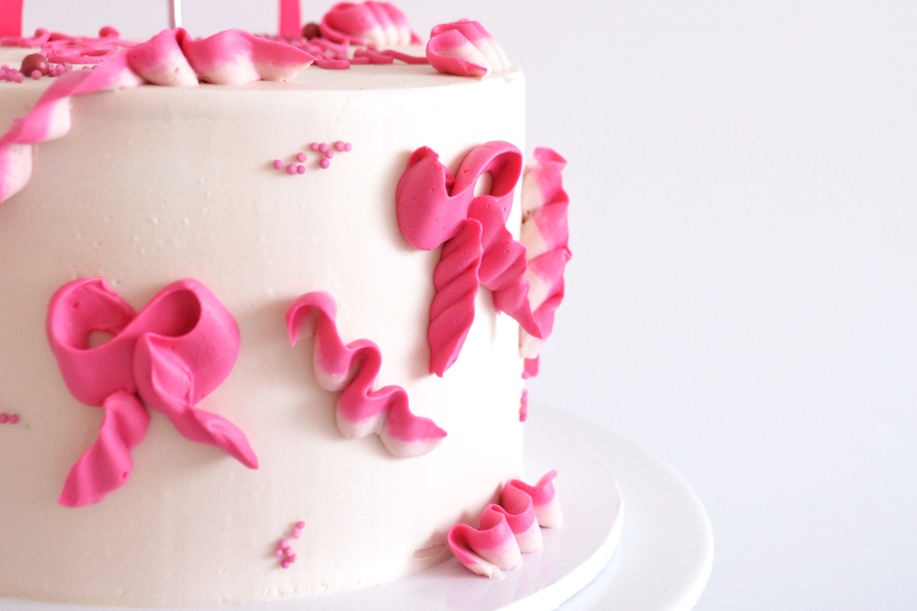White cake with pink decorations on a white background