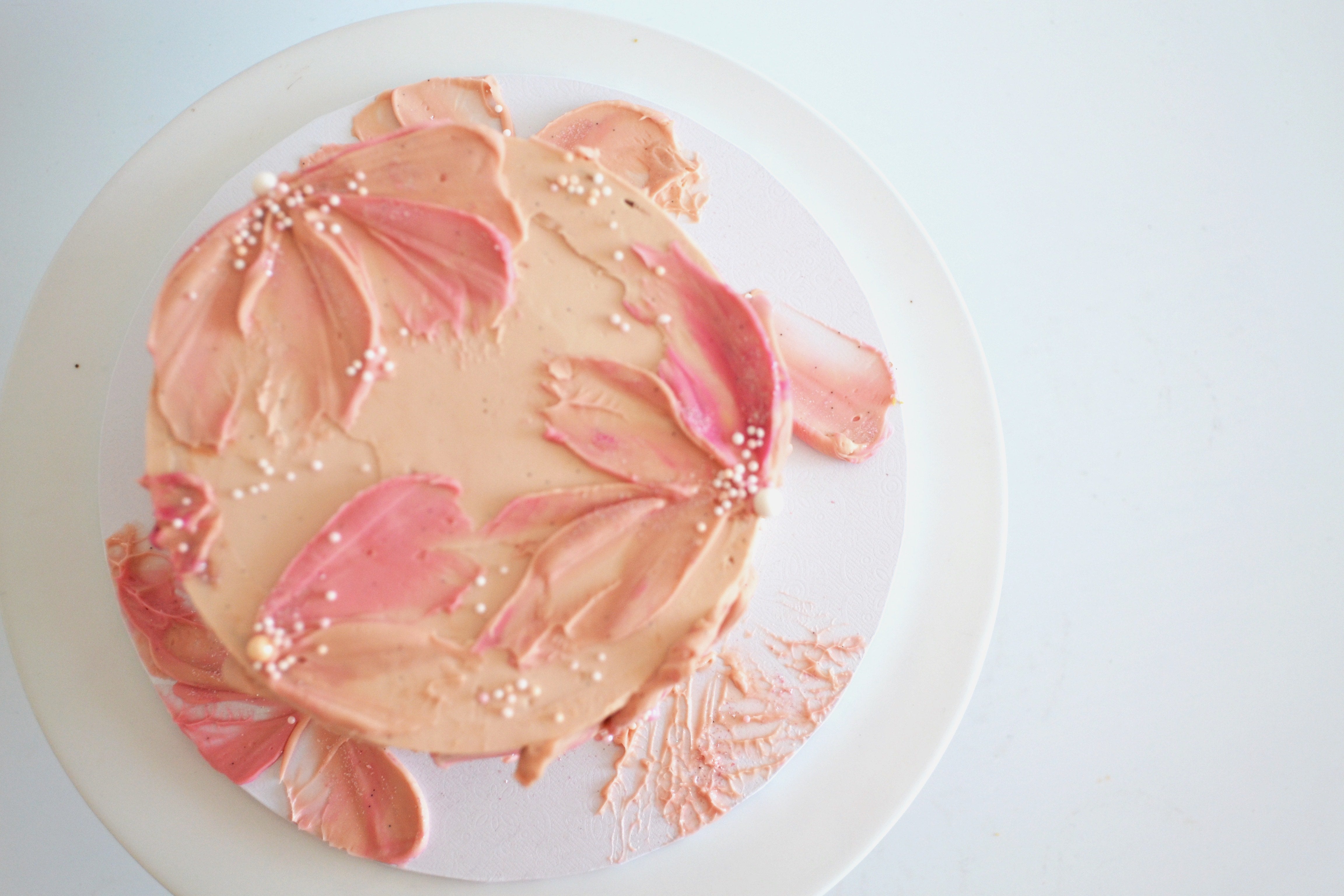 Pink floral cake on a white plate with a light background