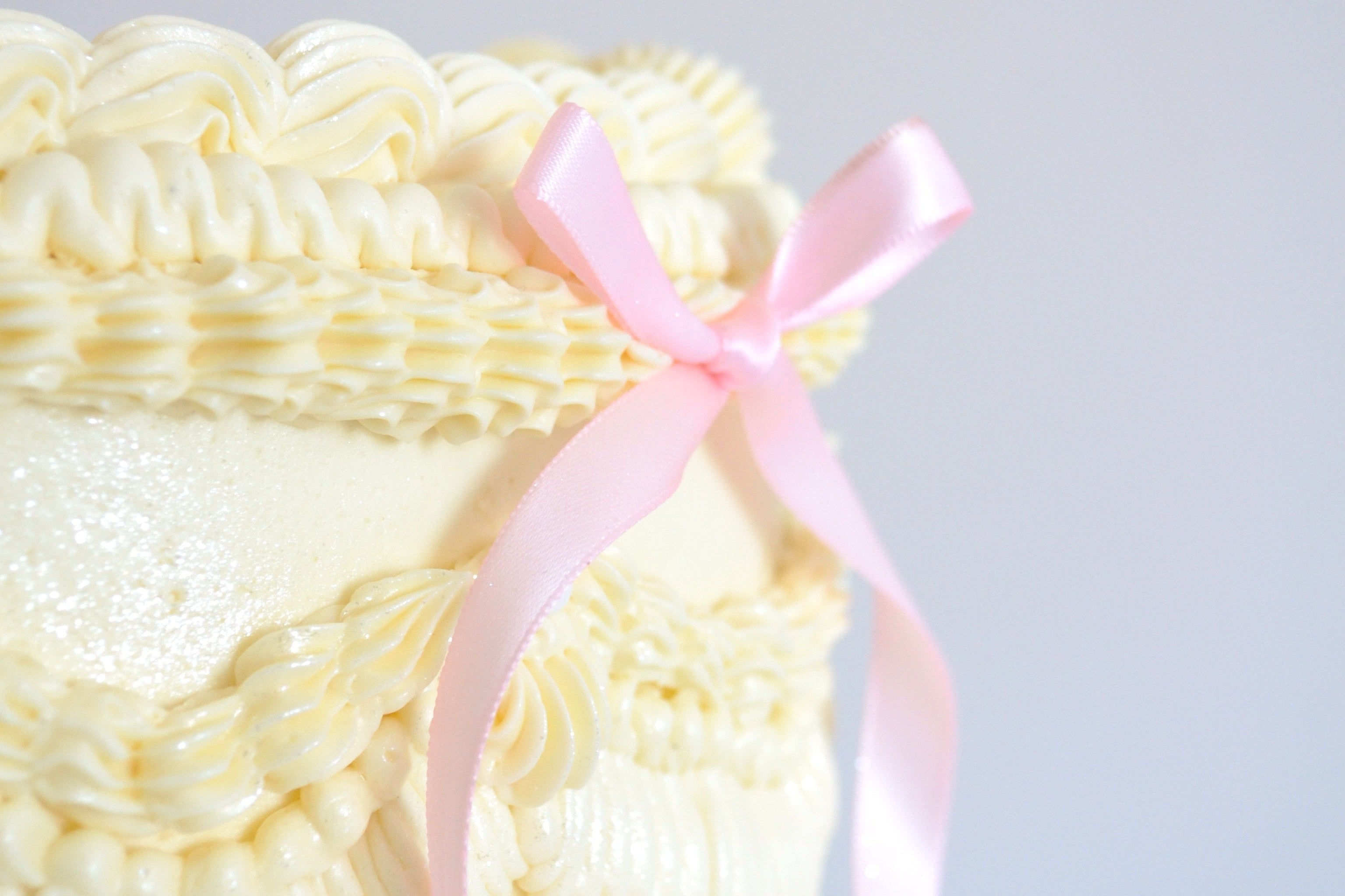 Ivory Piped Cake with a pink ribbon bow on the side